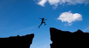 Man jumping across chasm to other side